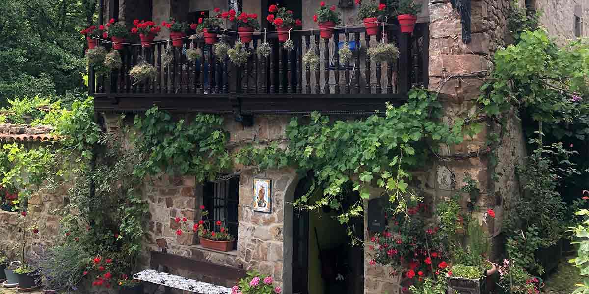 Una bonita casa de piedra repleta de flores de colores en el pueblo de Cantabria Bárcena Mayor