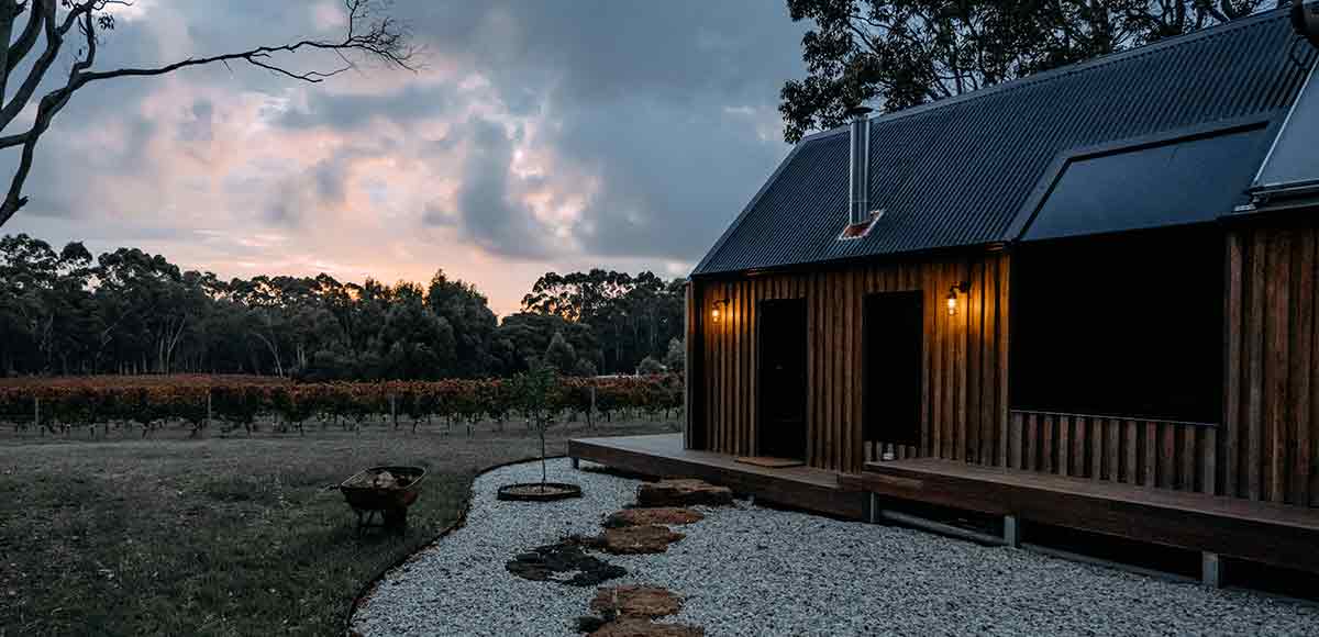 Una cabaña de madera con chimenea y piedras decorativas en el exterior