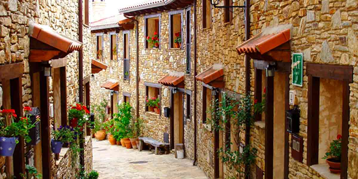 Vistas a una encantadora calle del centro histórico de Horcajo de la Sierra, repleta de flores rojas, plantas y paredes de piedra