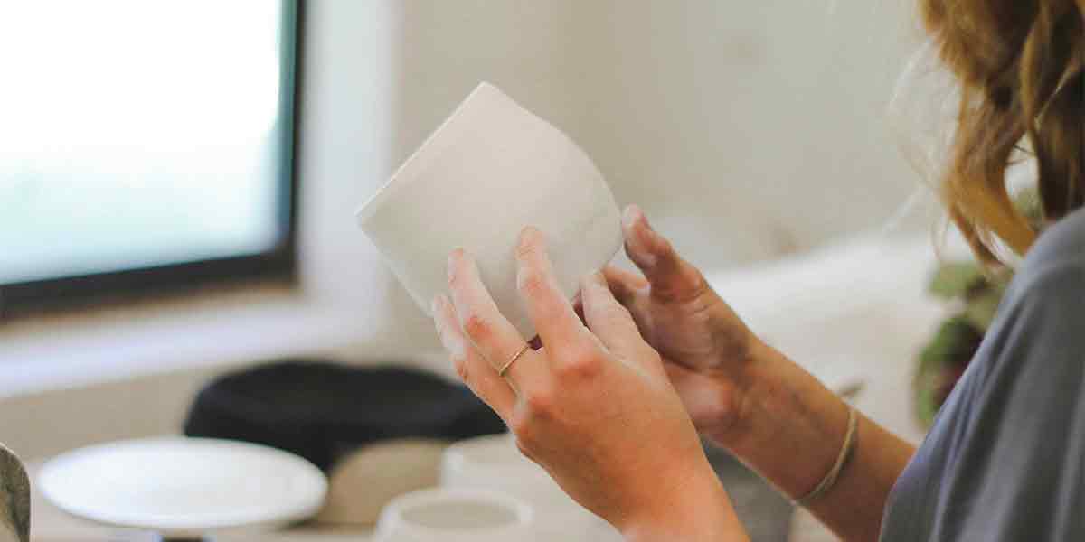 Una mujer haciendo una taza de cerámica con sus propias manos