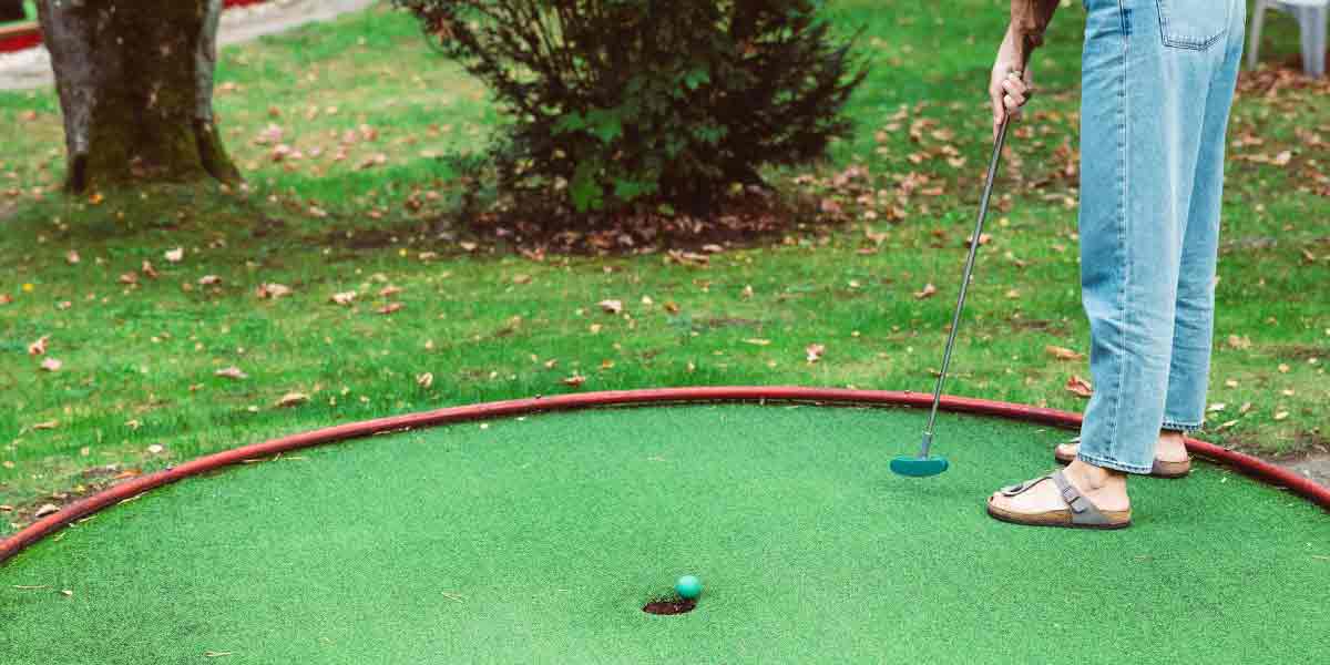 Una pareja jugando una partida de minigolf al aire libre, uno de los planes en pareja Madrid más singulares